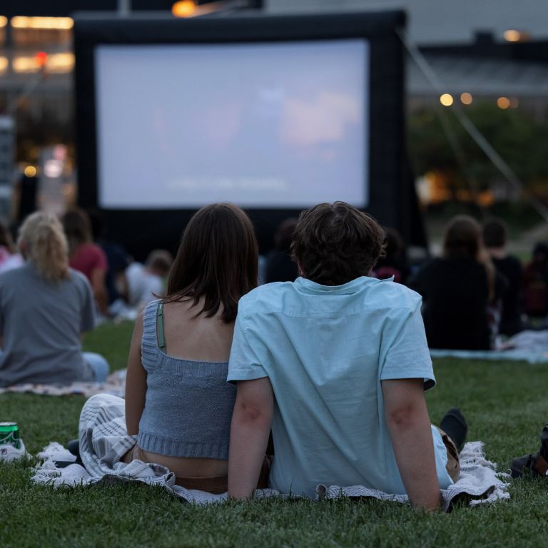 Two students enjoying a movie on the lawn at an event sponsored by SAPB.