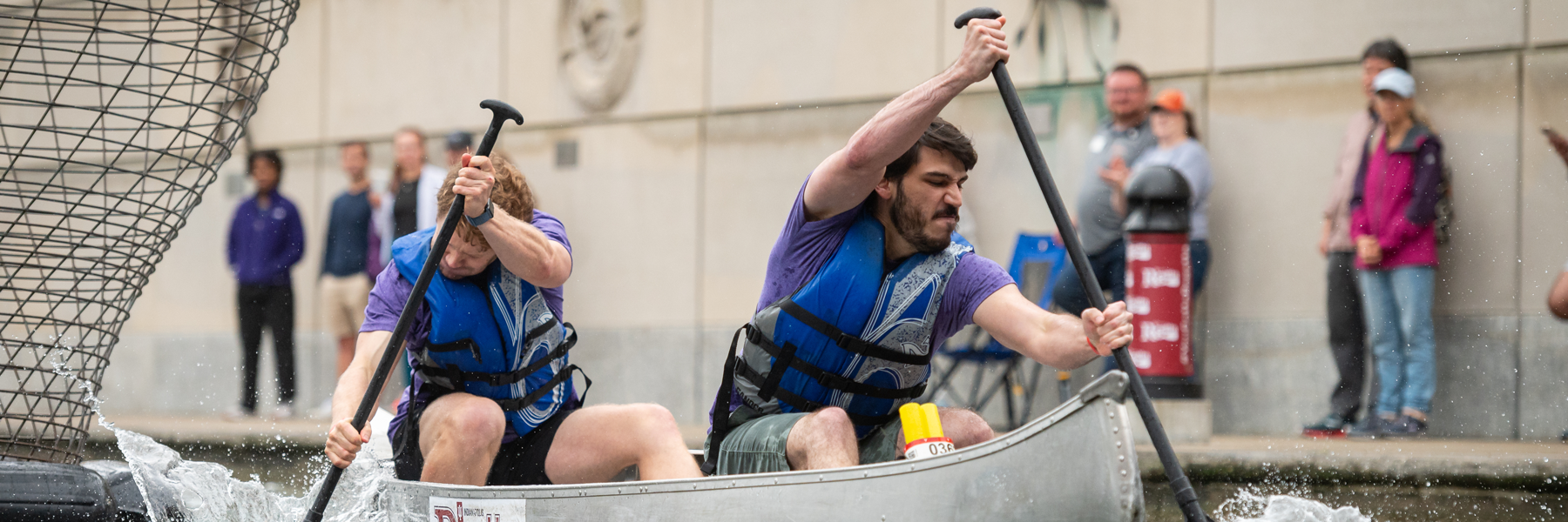 Two men in a boat rowing intensely.