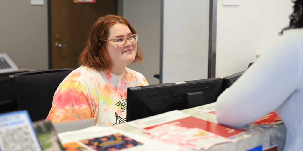 A student at the front desk answering a question from a resident.