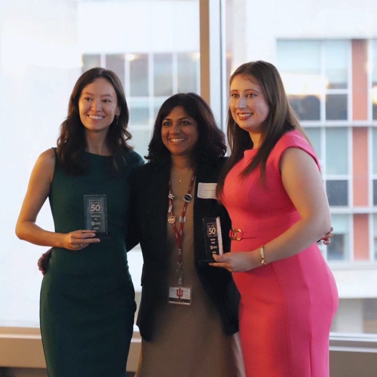 Three women posing for an award.