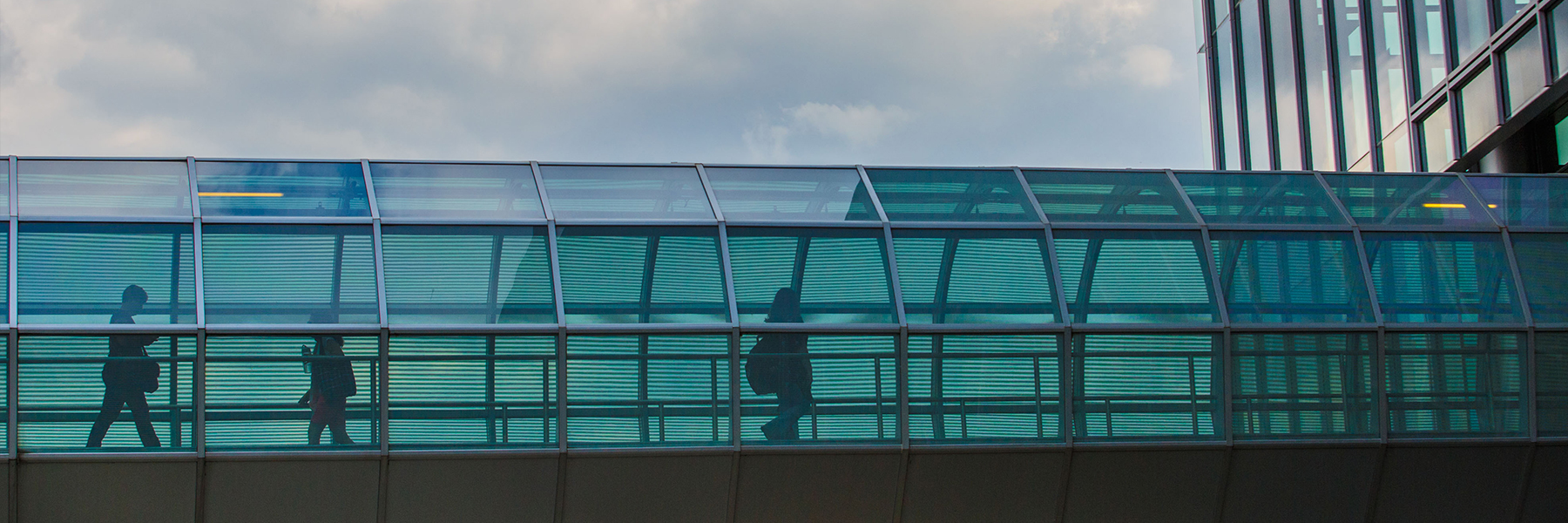 Silhouettes of people walk through the Campus Center tube.